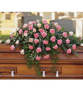 Pink and white floral casket spray on a wooden casket