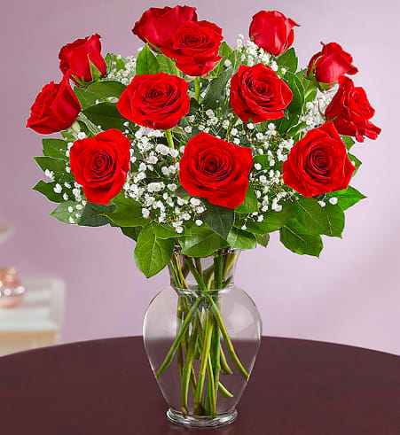 Red roses in a clear glass vase with baby's breath