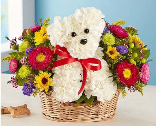 White teddy bear in a basket surrounded by colorful flowers