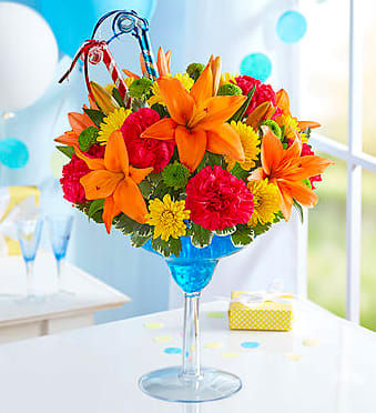 Bright mixed flower arrangement in a blue martini glass vase