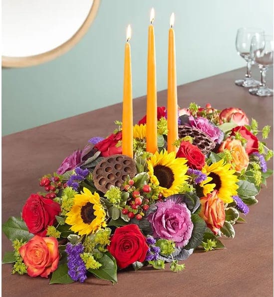 Garden Of Grandeur For Fall Centerpiece - Autumn gatherings call for a grand centerpiece. We’ve designed our luxurious arrangement with a mix of brightly colored blooms and unique, textural accents, creating a truly unique table display. A trio of orange candles provides the perfect finishing touch for spirited celebrations.
