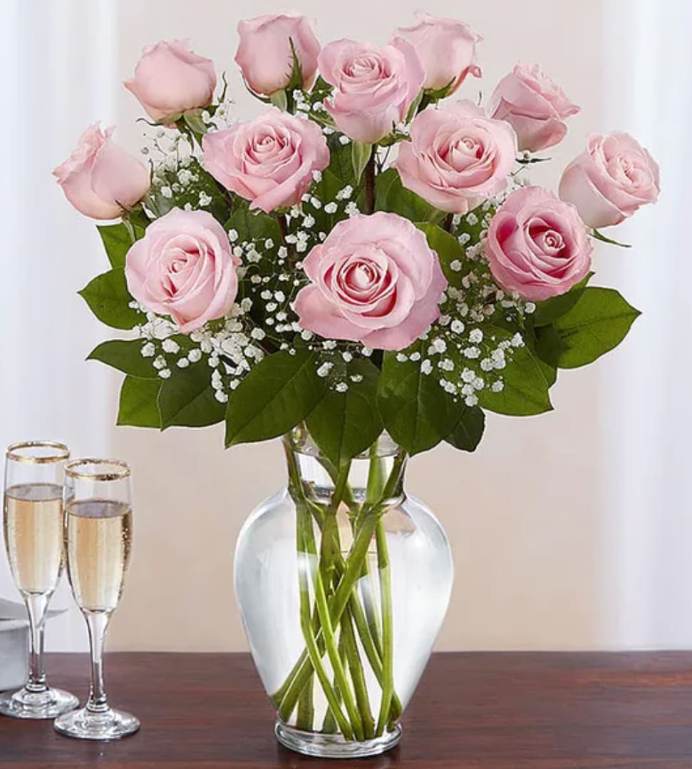 Pink roses arranged in a clear glass vase with baby's breath