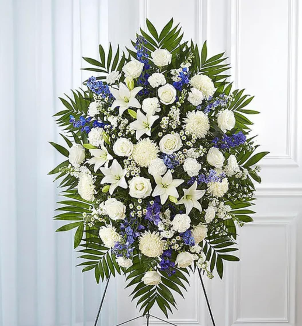 Standing funeral spray of white and blue flowers on an easel