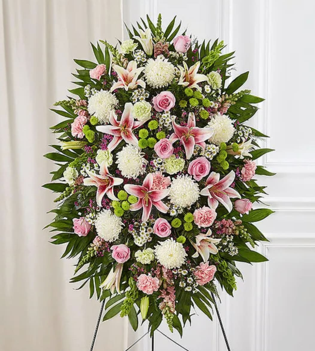 Standing floral spray with pink roses, lilies, and white mums on an easel