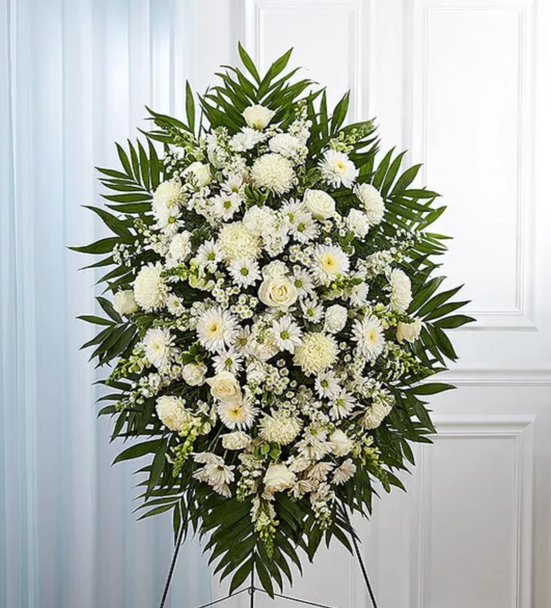 Large white floral standing spray with palm leaves on an easel
