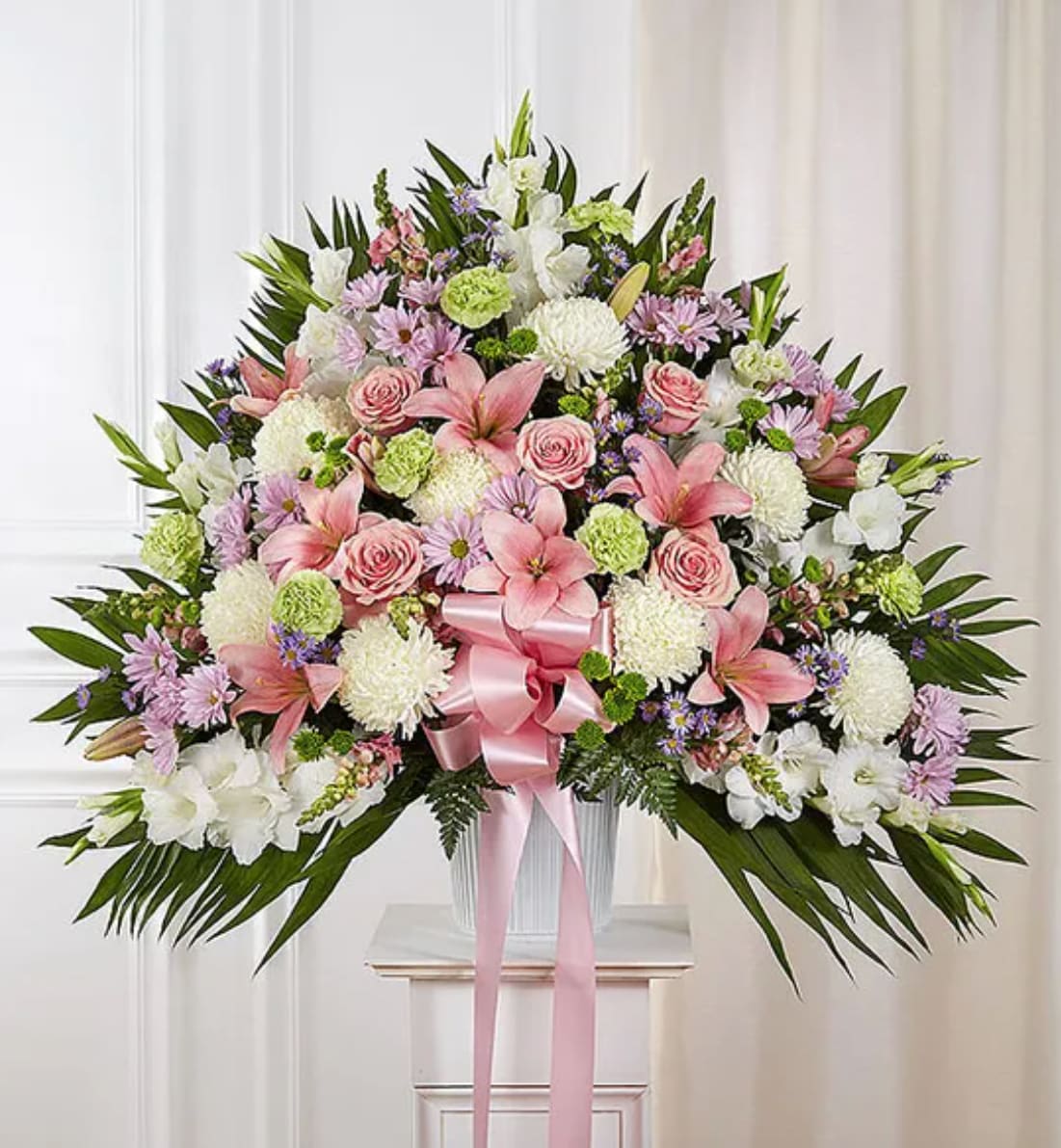 Large pink and white floral spray with a pink ribbon on a pedestal