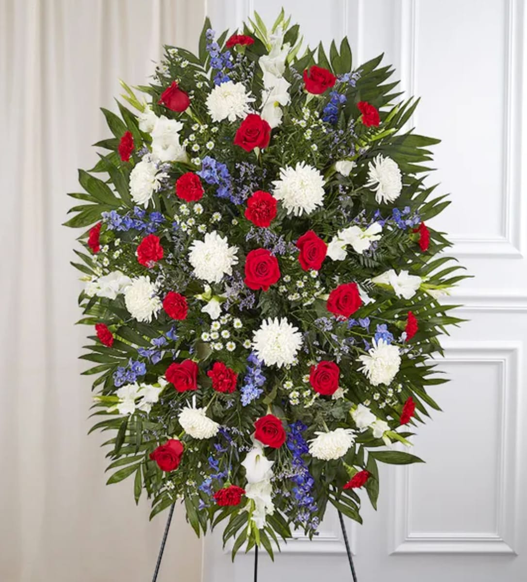 Standing floral spray with red roses, white blooms, and blue accents
