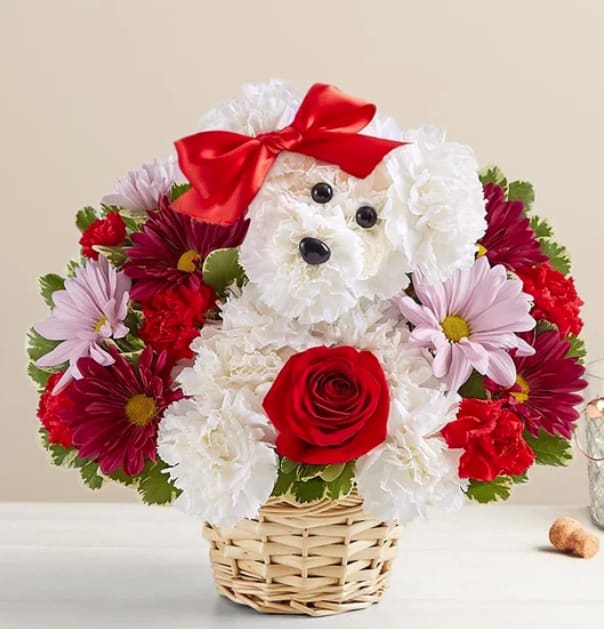Flower arrangement shaped like a white dog with a red bow in a basket