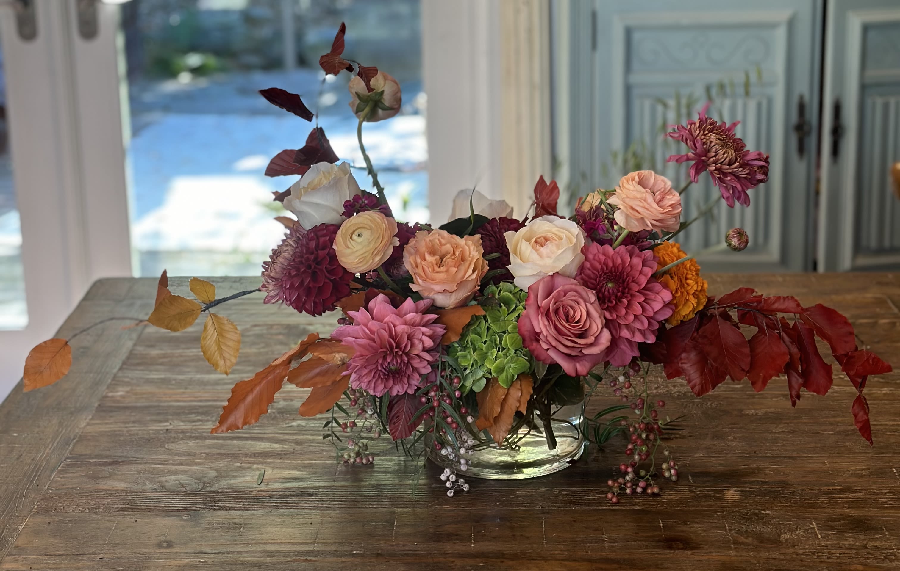 Mixed pink and peach flower arrangement in a clear glass bowl