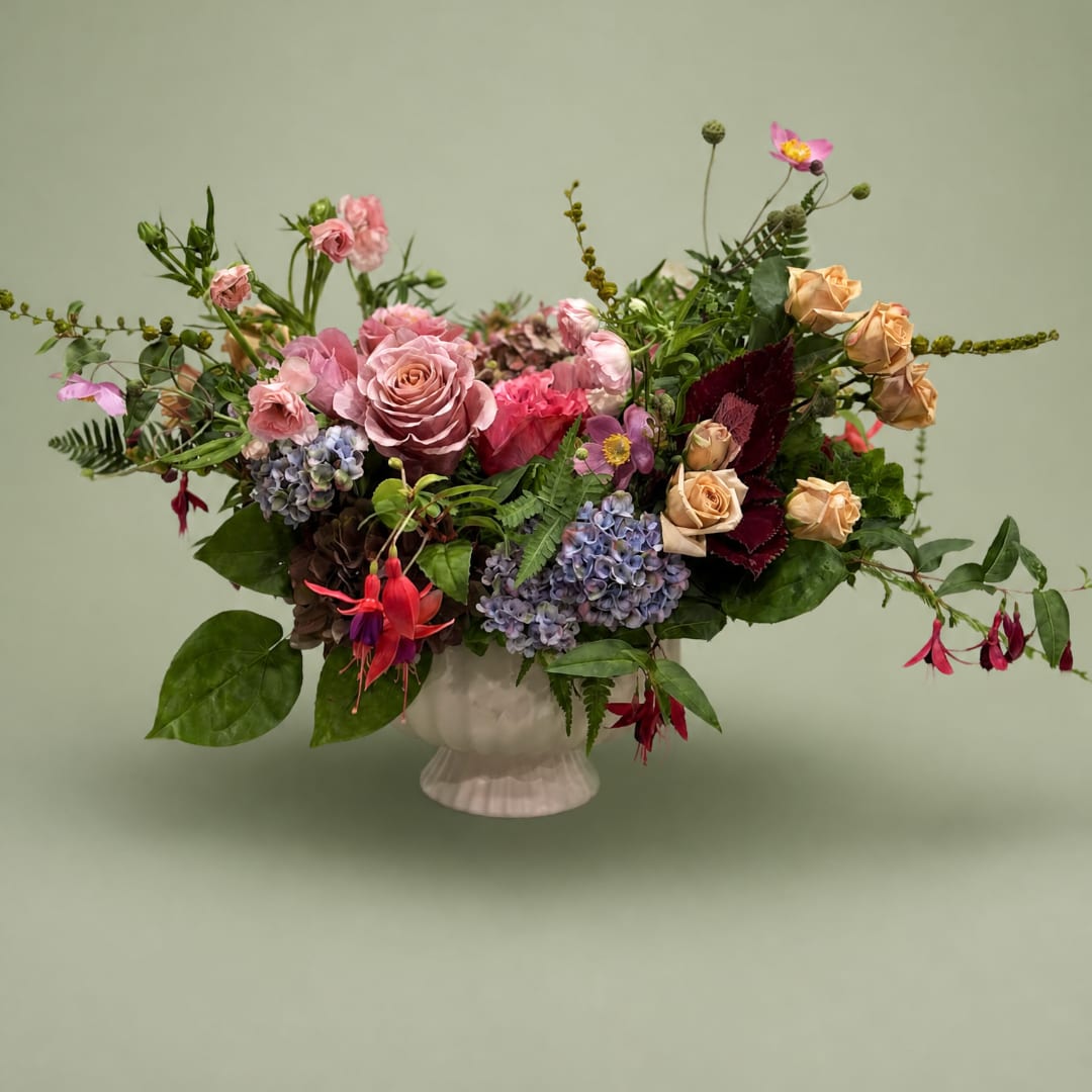 Mixed bouquet of pink and peach flowers in a white vase