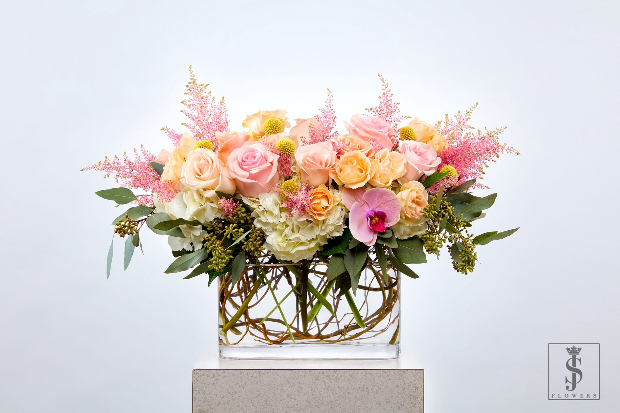 Pink and peach roses in a glass vase with pink filler flowers