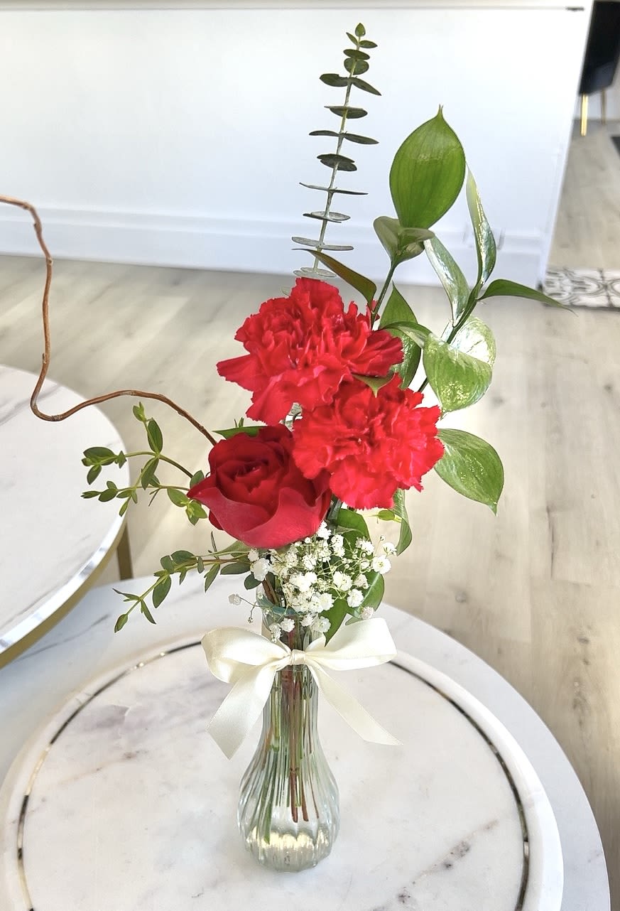 Red rose and carnations in a clear vase with a white ribbon