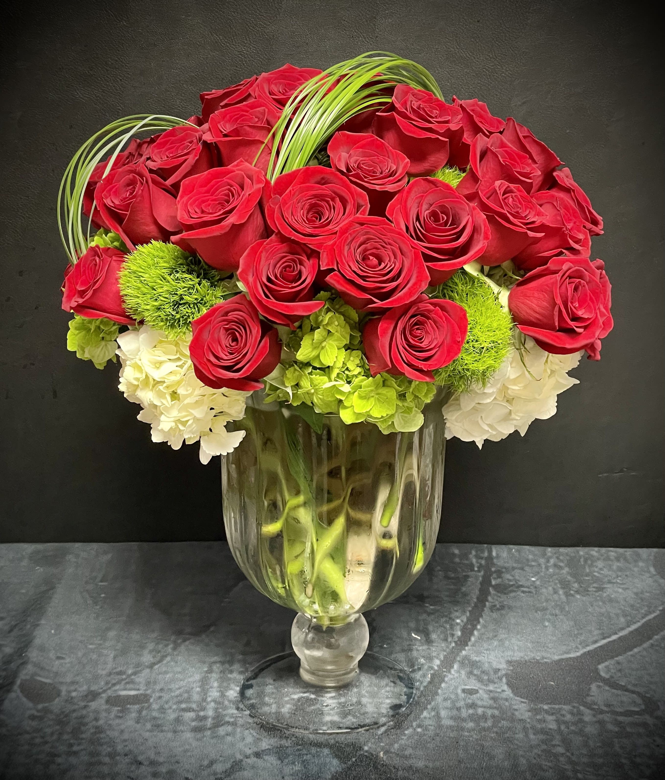 Red Everlasting - 3 dozen of red roses, white and green hydrangeas, dianthus, bear grass, and eucalyptus in a crystal glass vase.