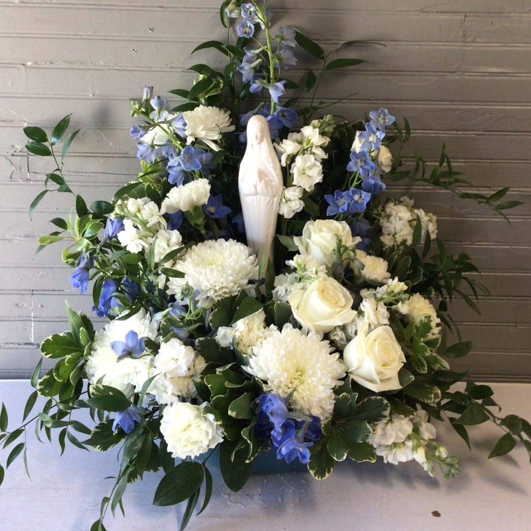 White floral arrangement with blue flowers and a small statue centerpiece