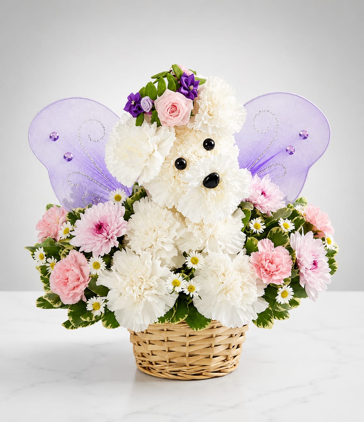 Butterfly Wishes Puppy™ - Butterfly Wishes Puppy is a charming handcrafted floral puppy made with fresh white carnations and accented with soft pink blooms, delicate daisies, and whimsical butterfly wings. Arranged in a natural woven basket, this enchanting design is a beautiful gift for birthdays, baby showers, congratulations, get well wishes, or simply to brighten someone's day.