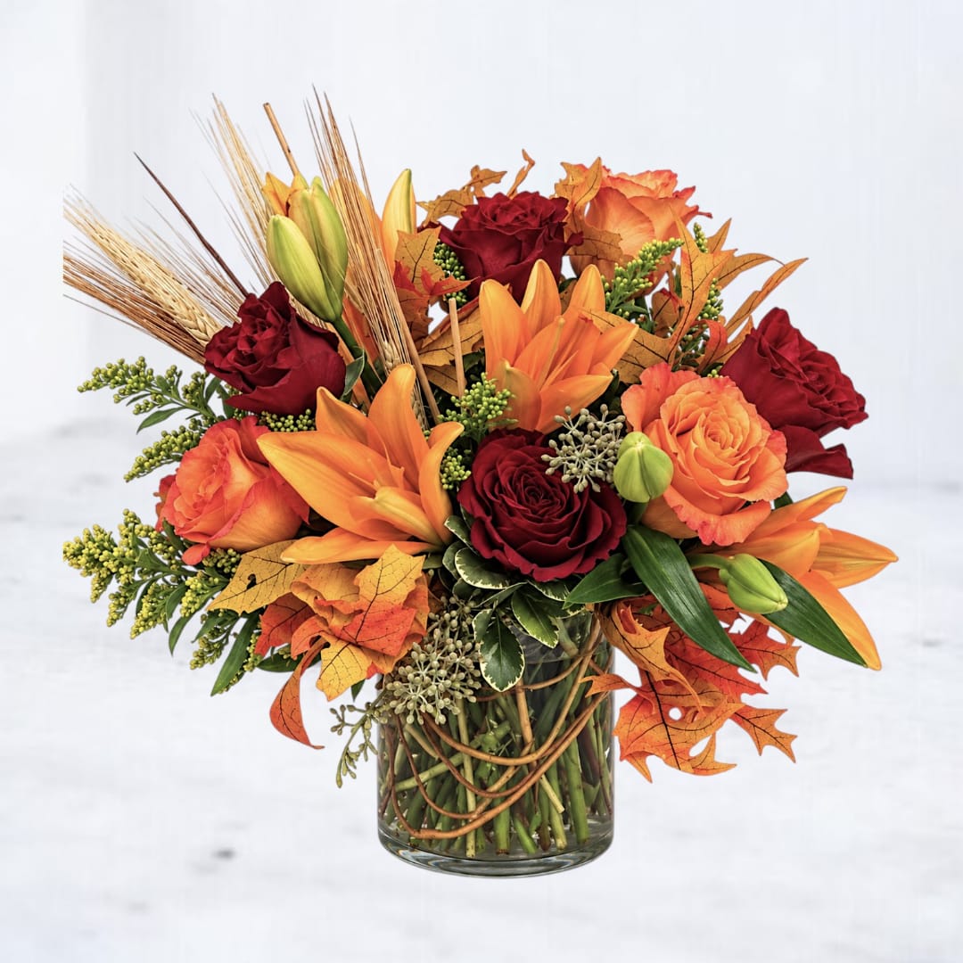Autumn bouquet of orange lilies and red roses in a glass vase