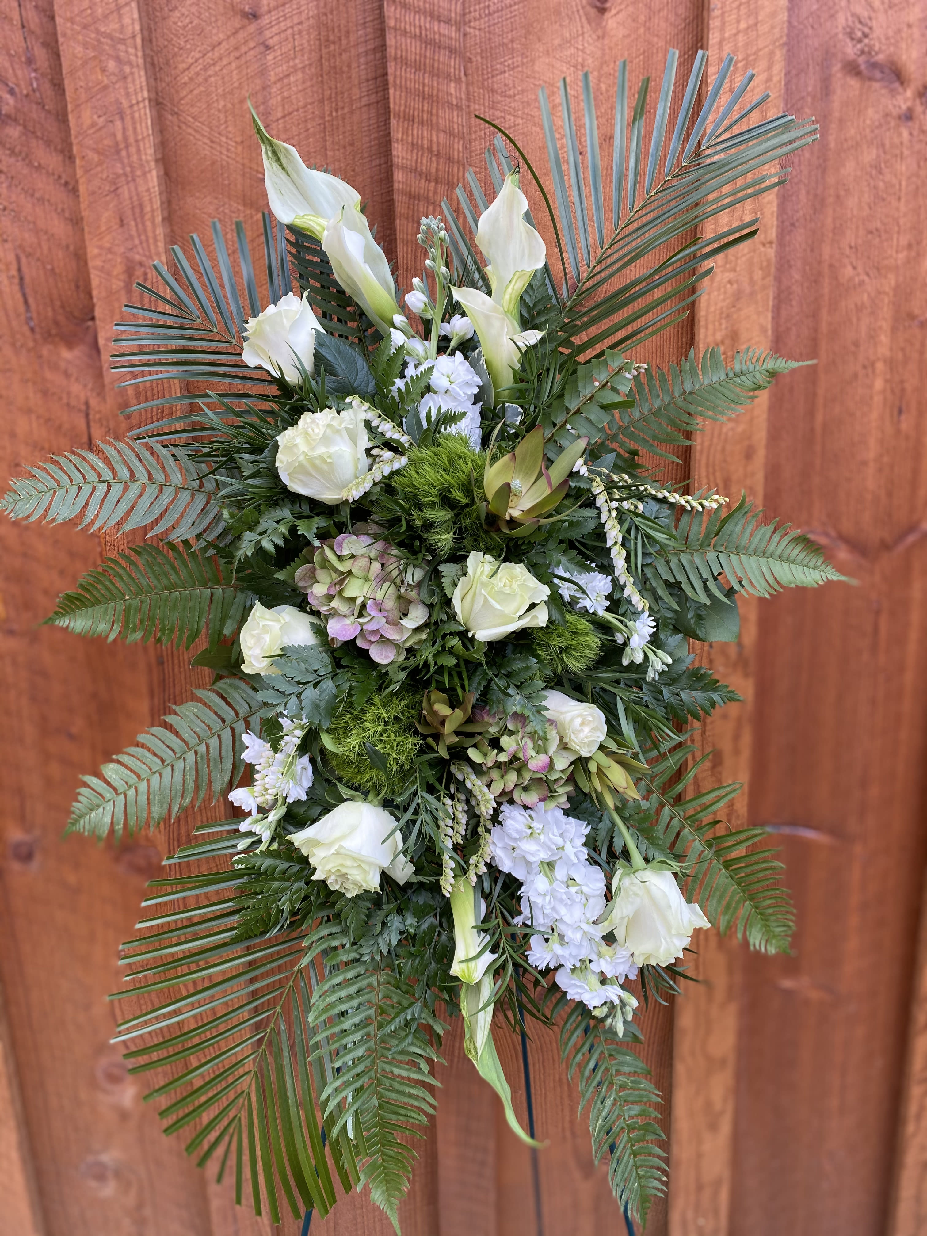 White floral standing spray with palm fronds and greenery