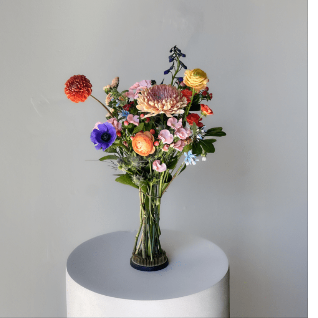 Colorful mixed bouquet in a clear glass vase on a pedestal