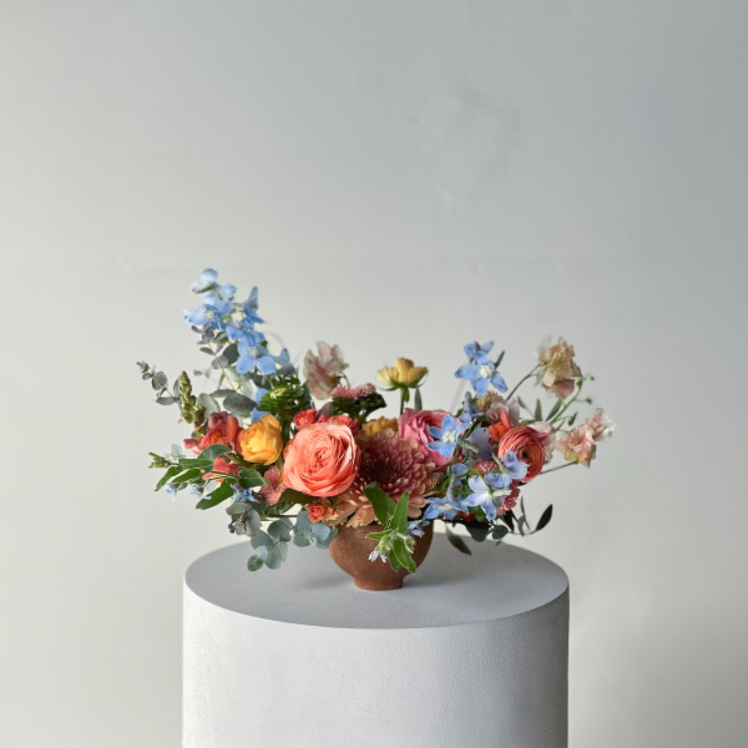 Mixed bouquet of colorful flowers in a small brown vase