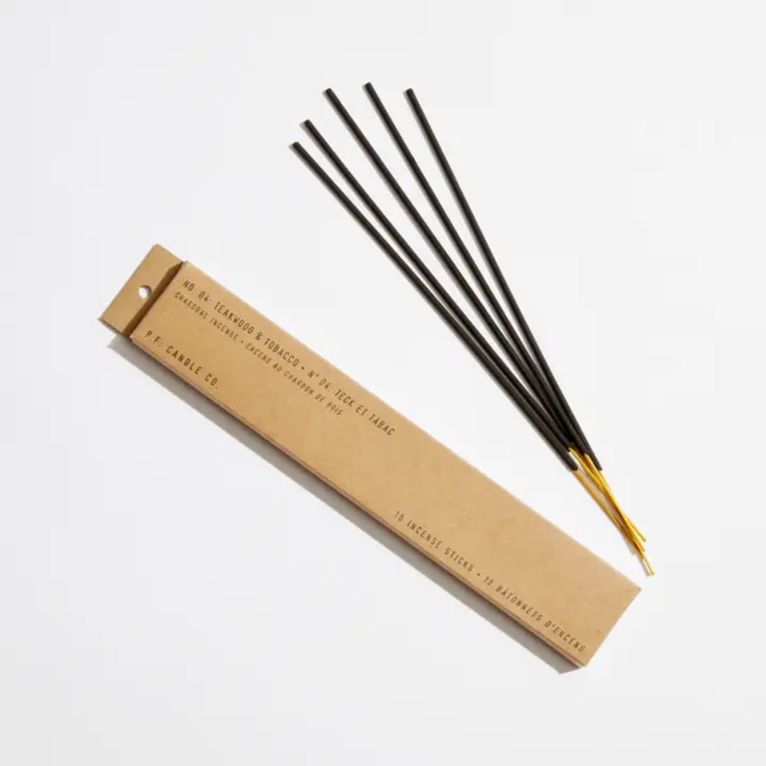 Box of incense sticks with several black sticks laid beside it