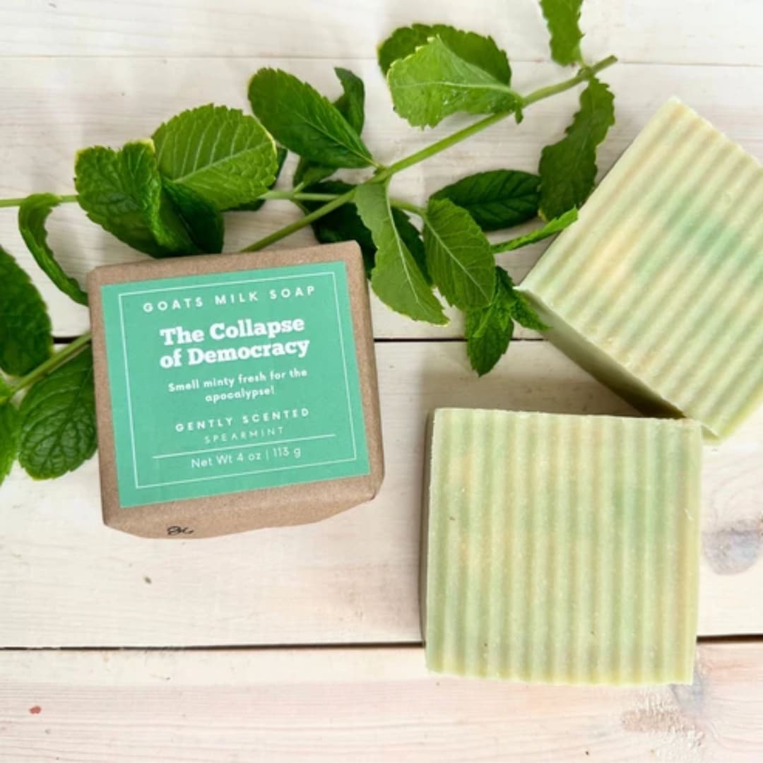 Mint-green soap bars with mint sprigs on a white wooden surface
