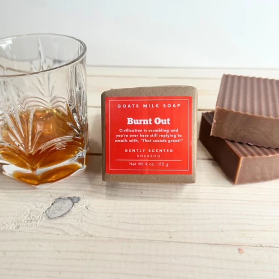 Soap bars beside a glass of amber liquid on a wooden surface