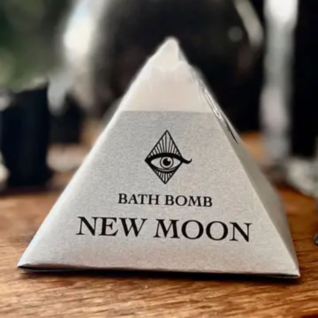 Triangular bath bomb package labeled New Moon on a wooden surface