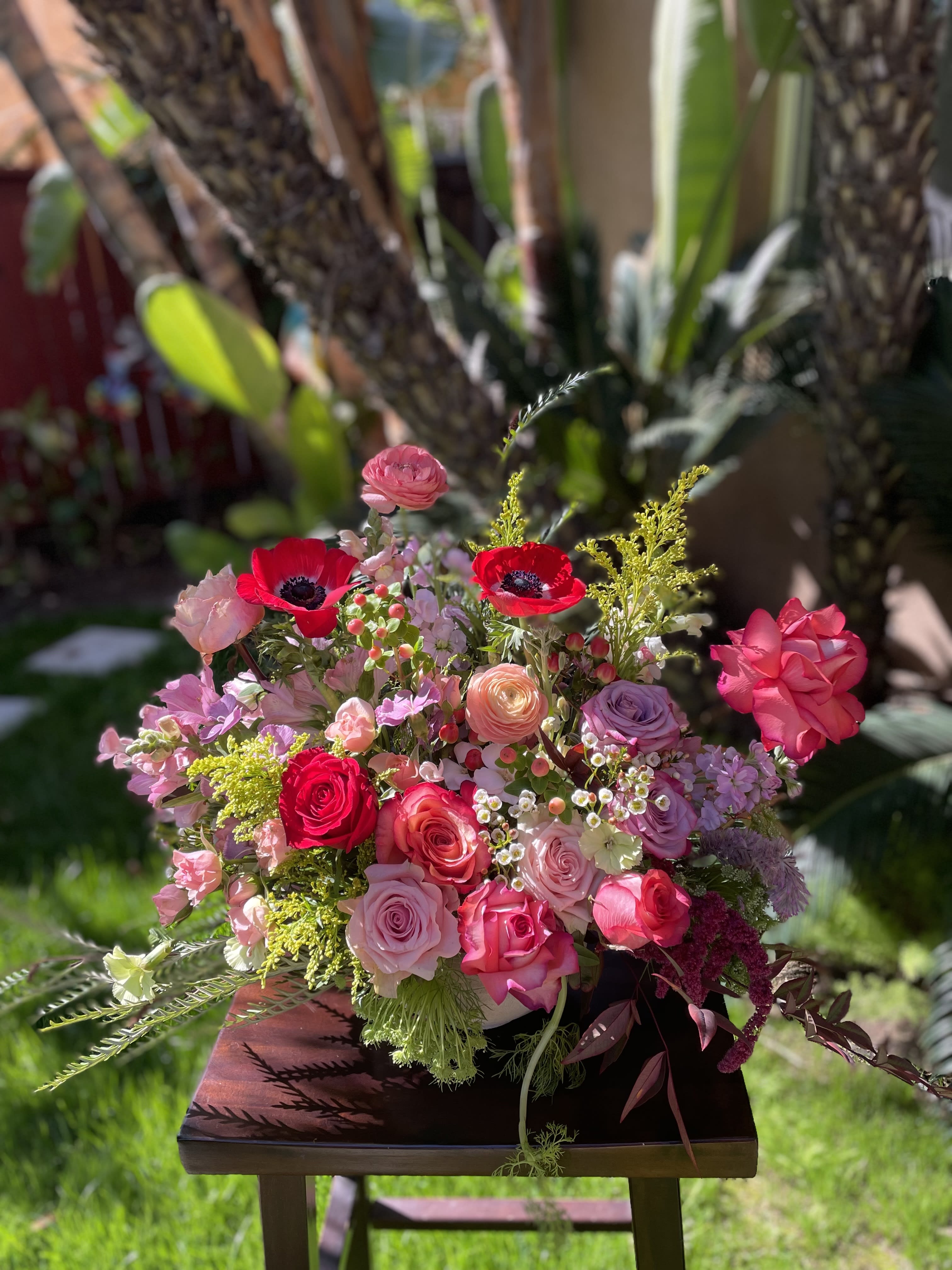 Mixed pink and red flower arrangement with roses and anemones