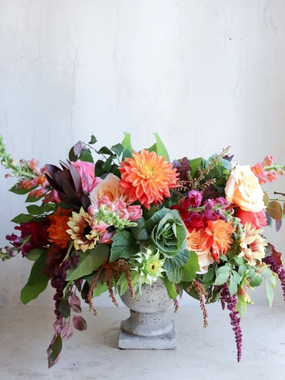 Large mixed flower arrangement in a stone pedestal vase