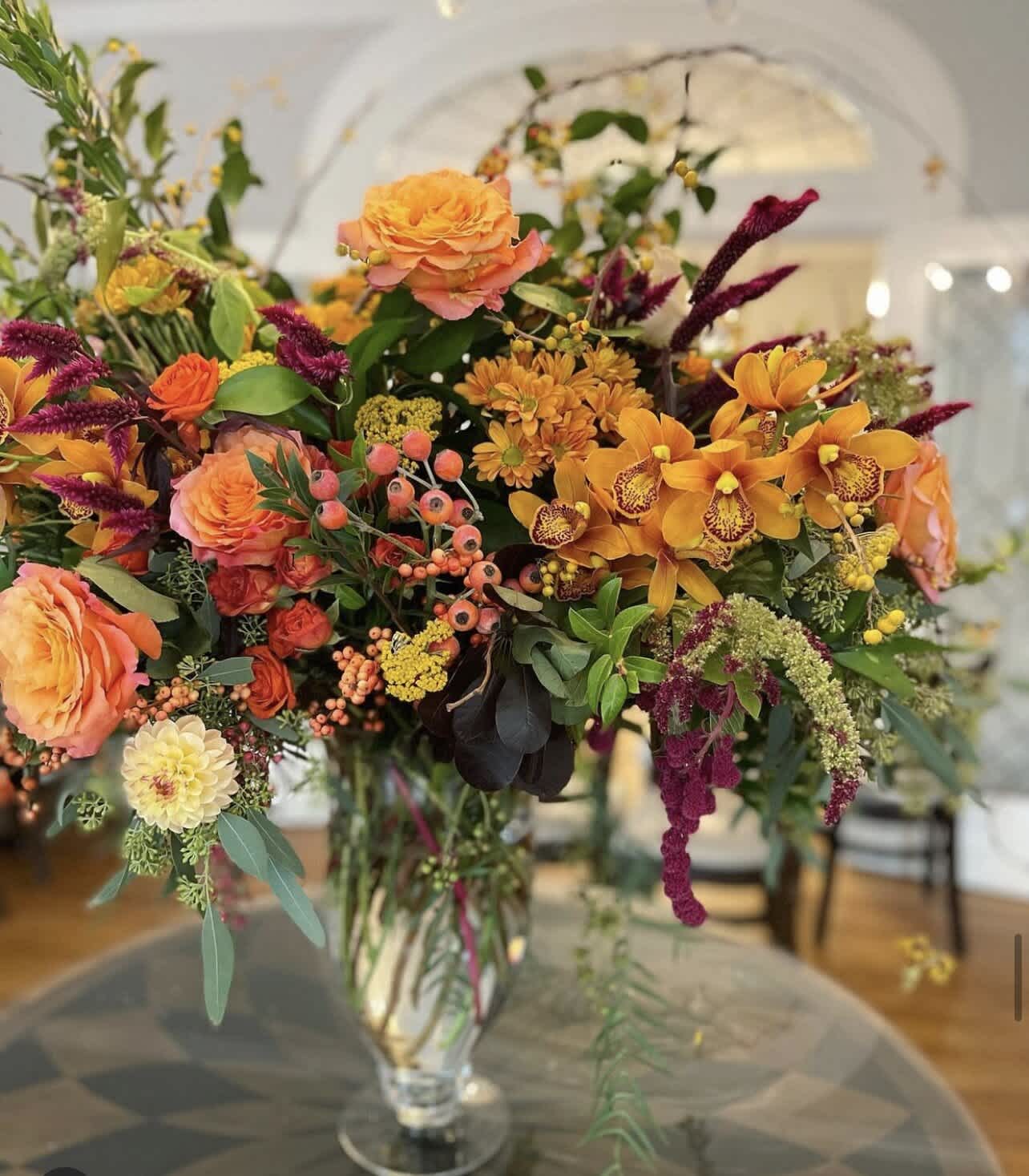 Mixed orange and purple floral arrangement in a clear glass vase