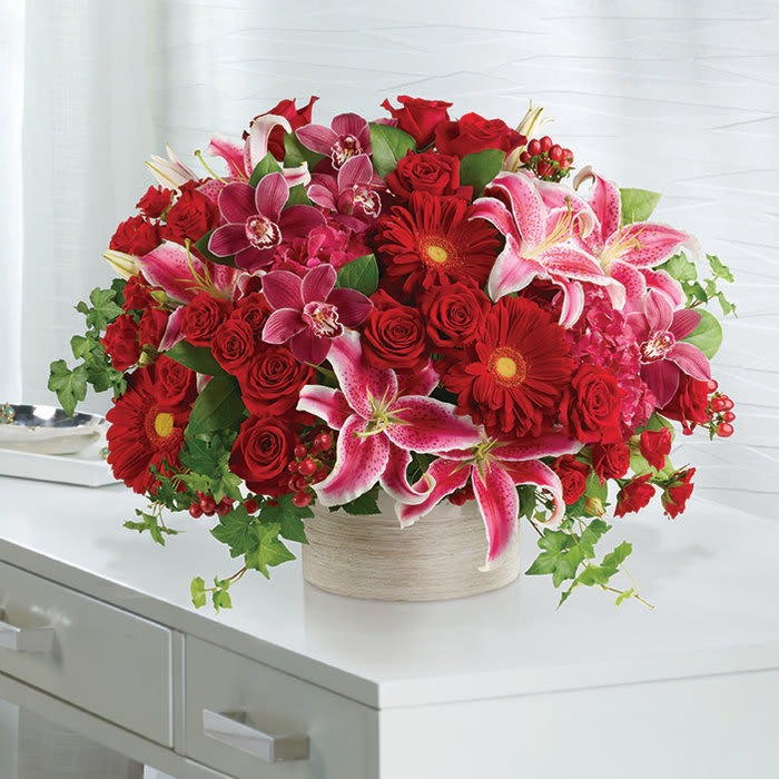 Bouquet of red roses, pink lilies, and red gerbera daisies in a round vase