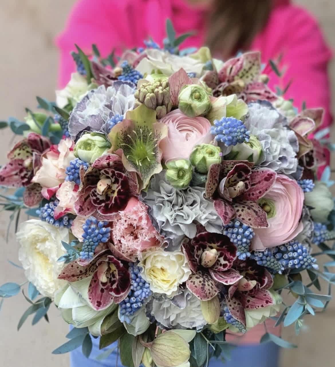 Pastel bouquet with orchids, ranunculus, and blue berry-like accents