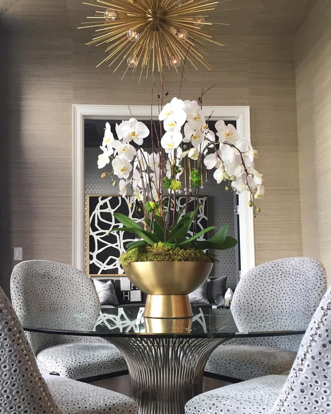 Tall white orchid arrangement in a gold bowl on a table