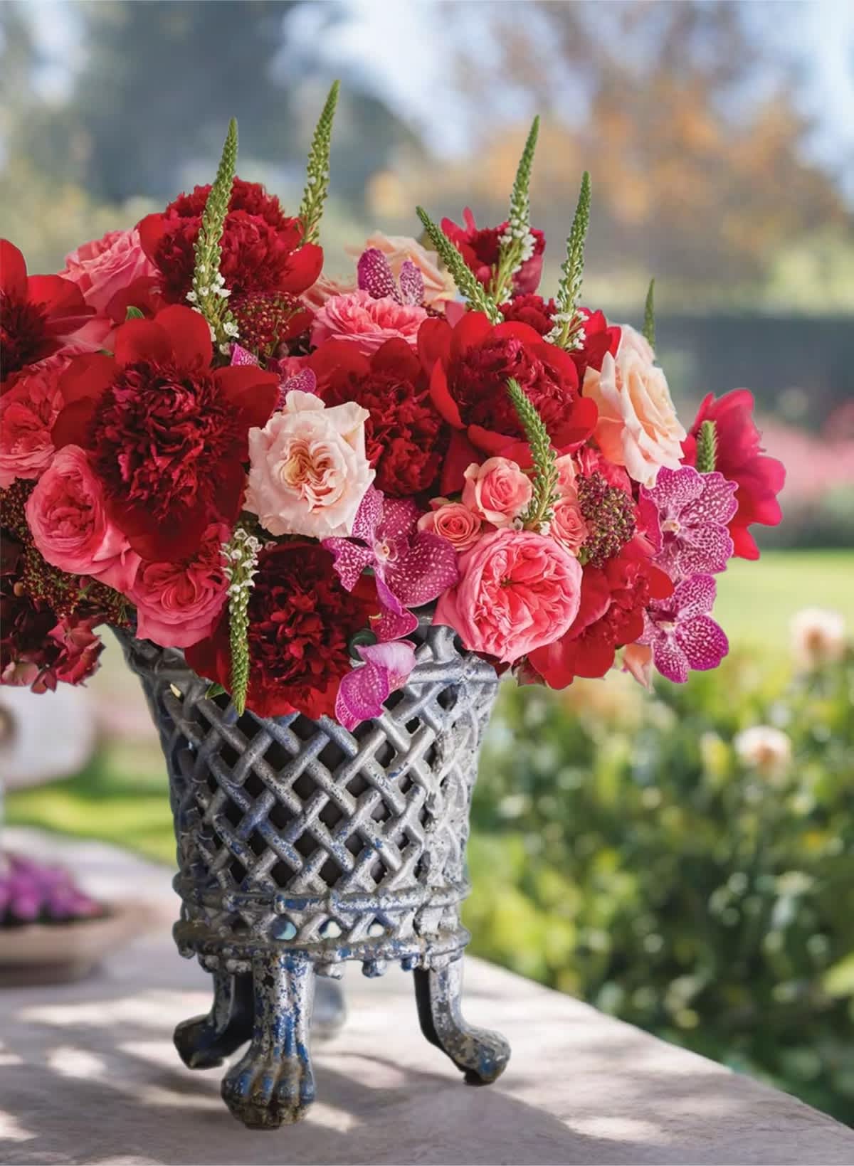 Red and pink floral arrangement in a decorative metal vase