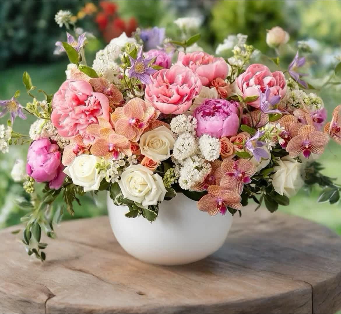 Pink and white floral arrangement in a white bowl vase