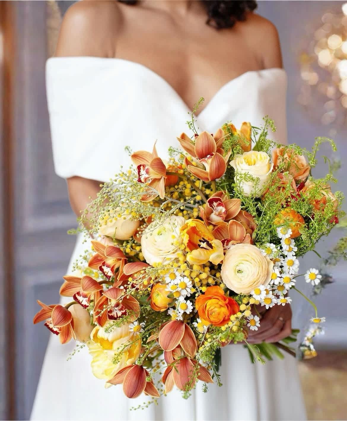 Bride holding a bouquet of orange and cream flowers