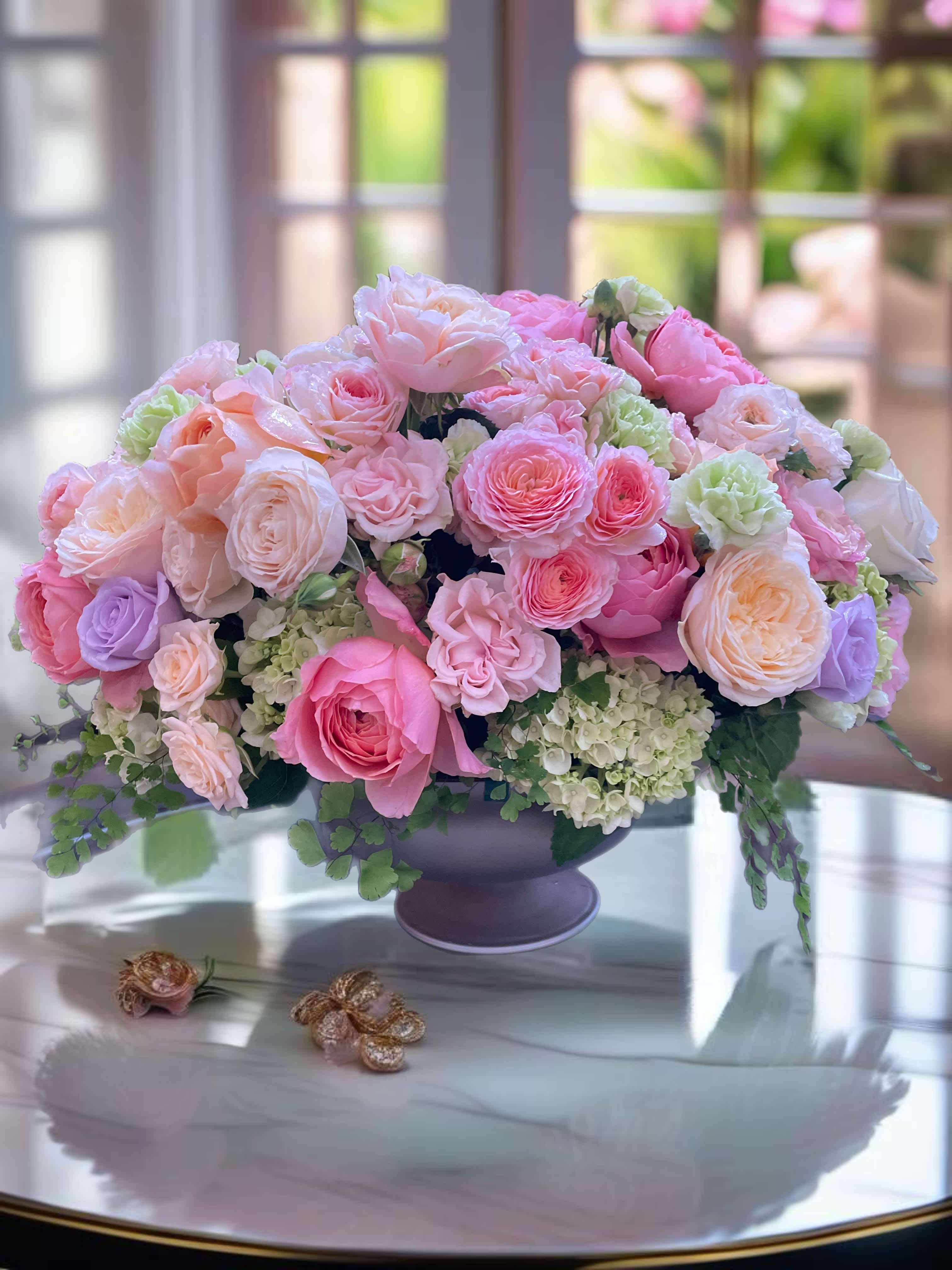 Pink and peach rose arrangement in a dark vase