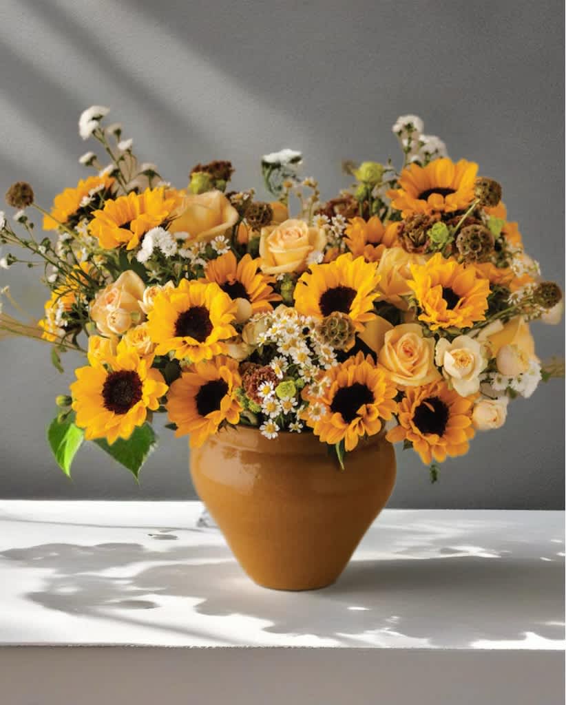 Sunflower and peach rose arrangement in a terracotta vase