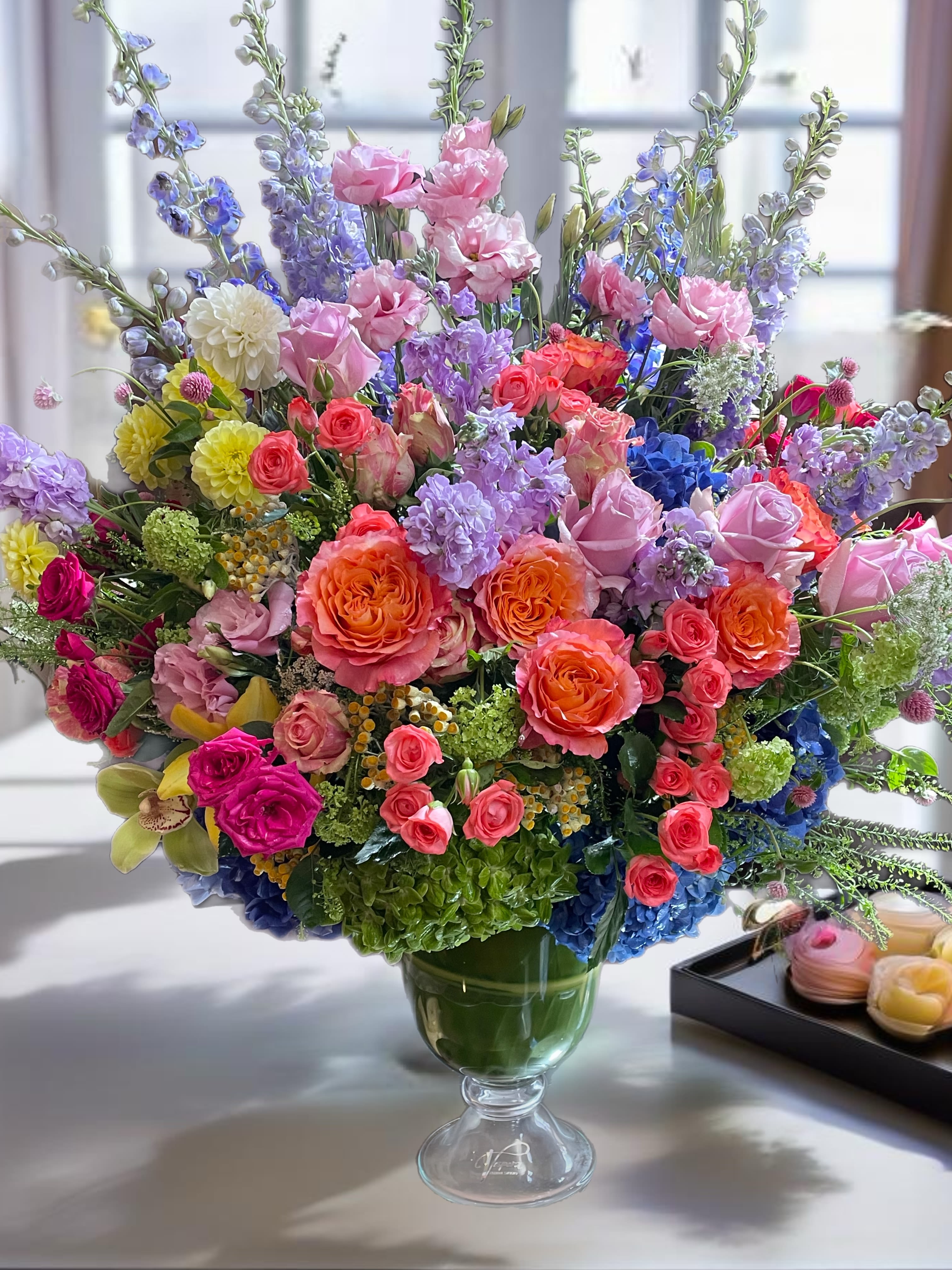 Large mixed bouquet of roses, hydrangeas, and lavender flowers in a glass vase