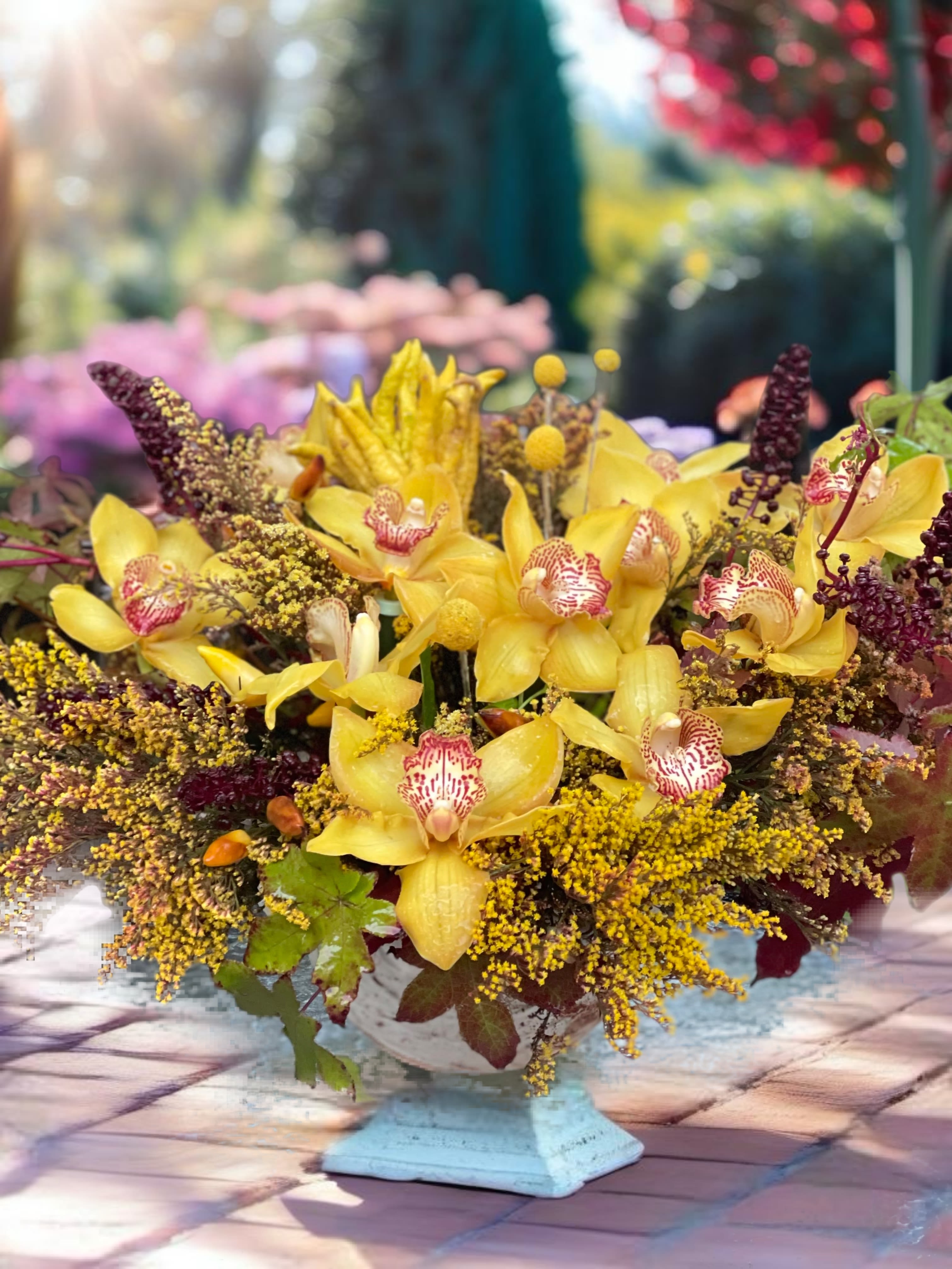 Yellow orchids arranged in a low white pedestal container