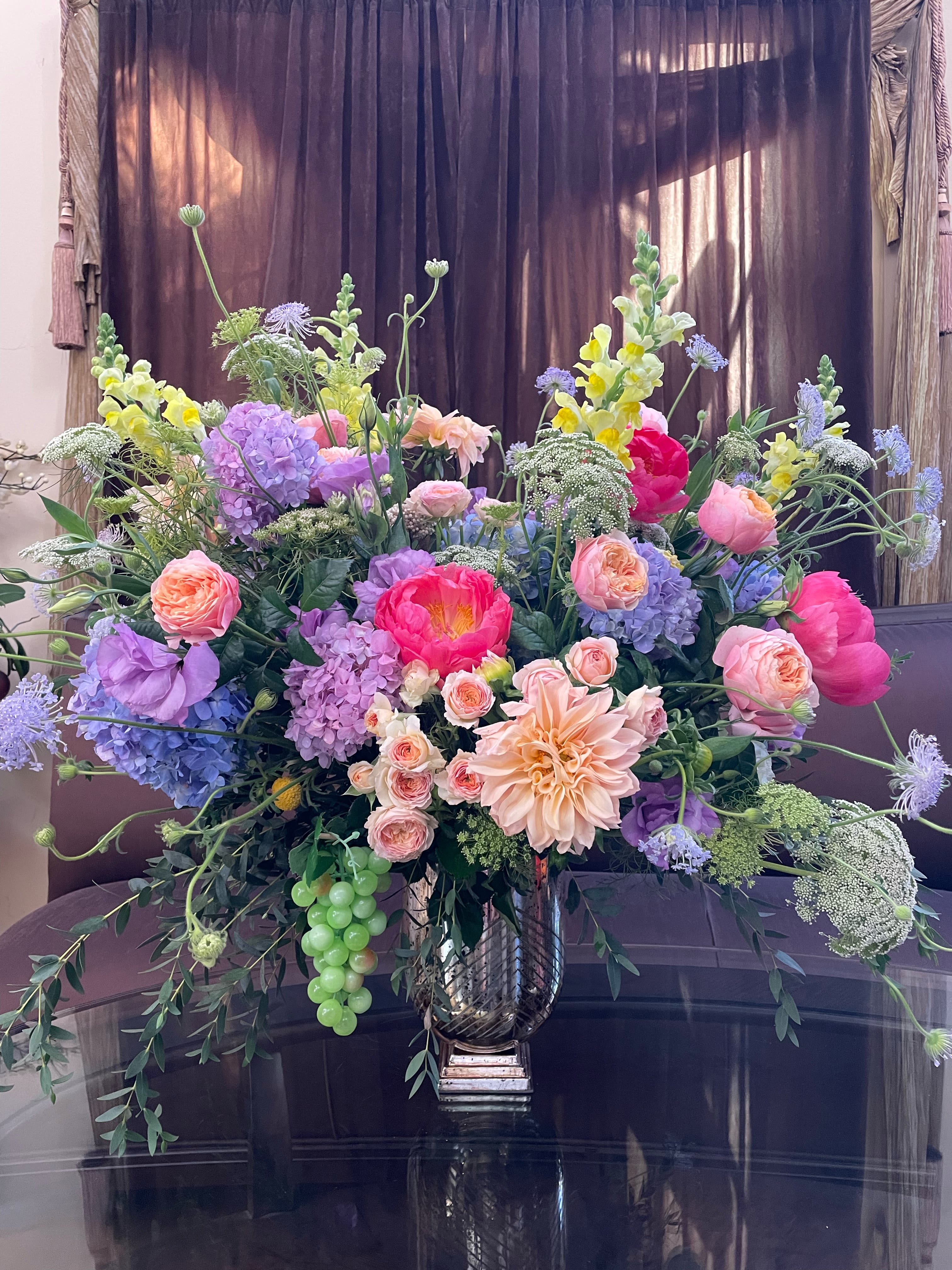 Large mixed bouquet in a metallic vase with pink, purple, and yellow blooms