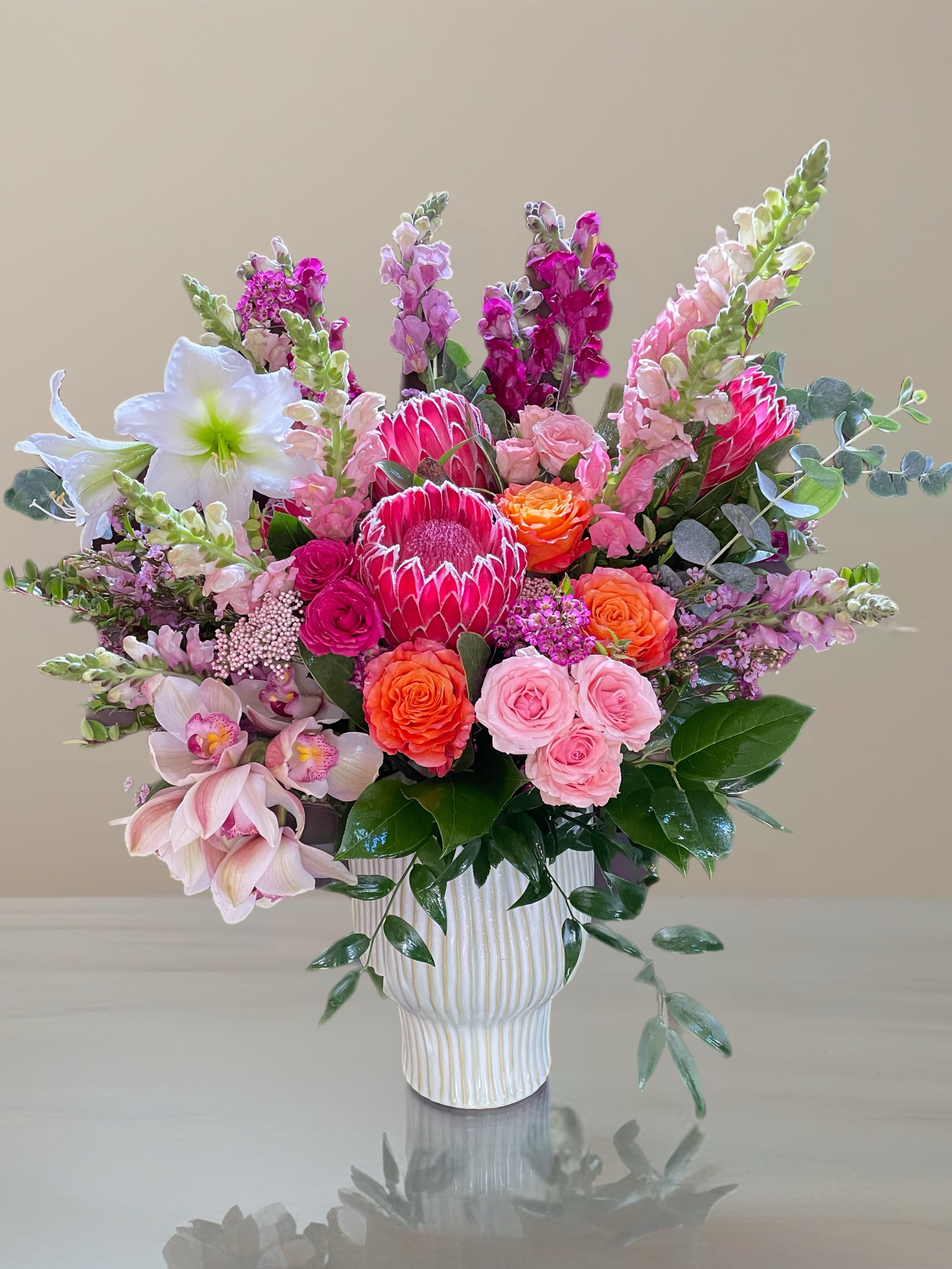 Pink and orange mixed flower arrangement in a white vase