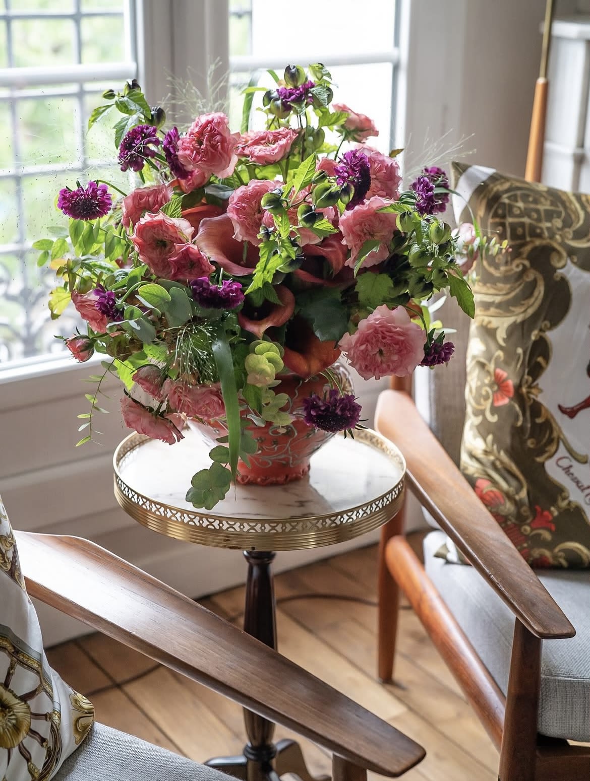 Pink and purple floral arrangement in a decorative vase on a small table