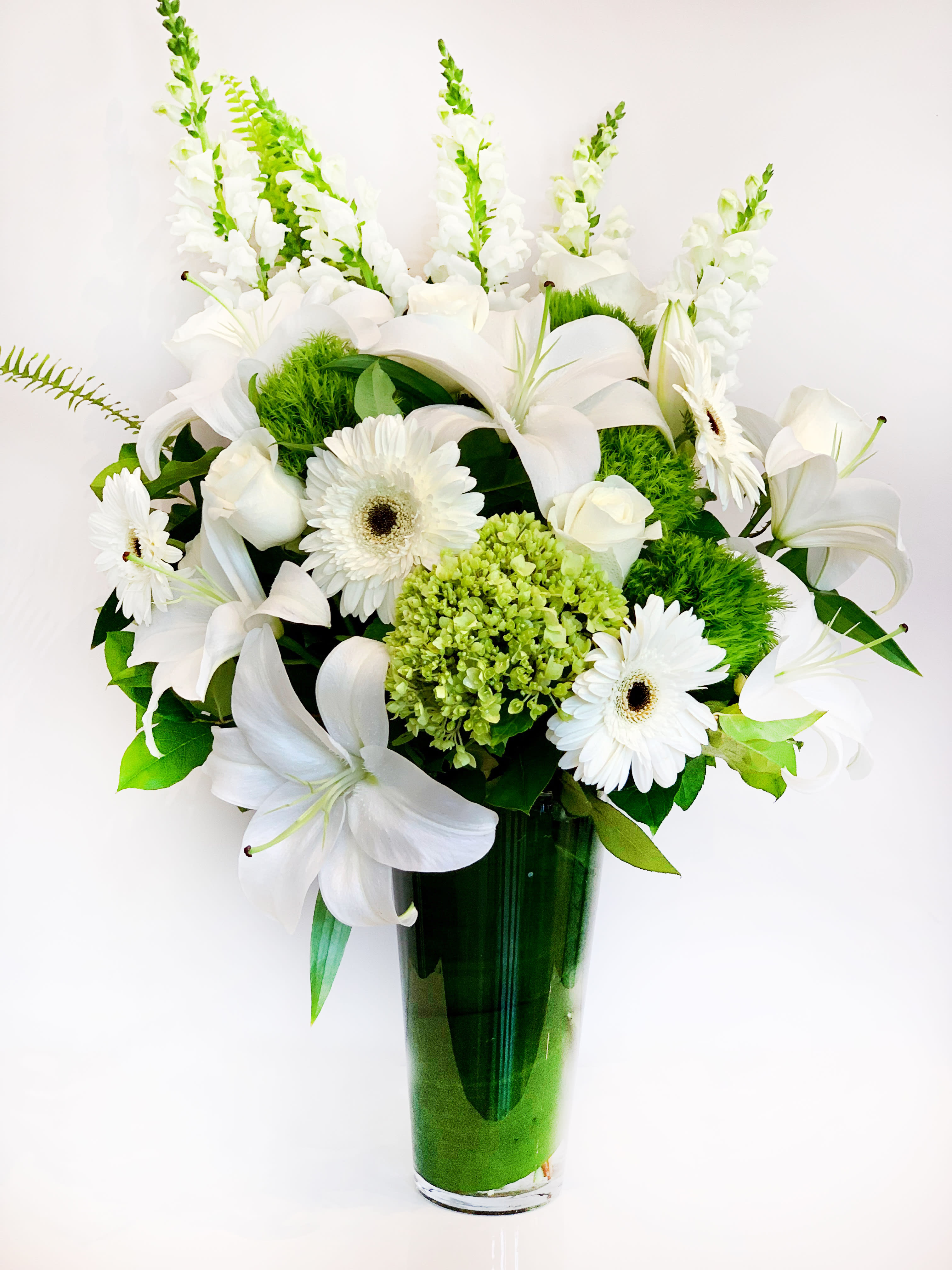 White lilies and gerbera daisies in a green glass vase