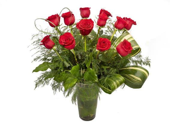 Red roses arranged in a clear glass vase with greenery