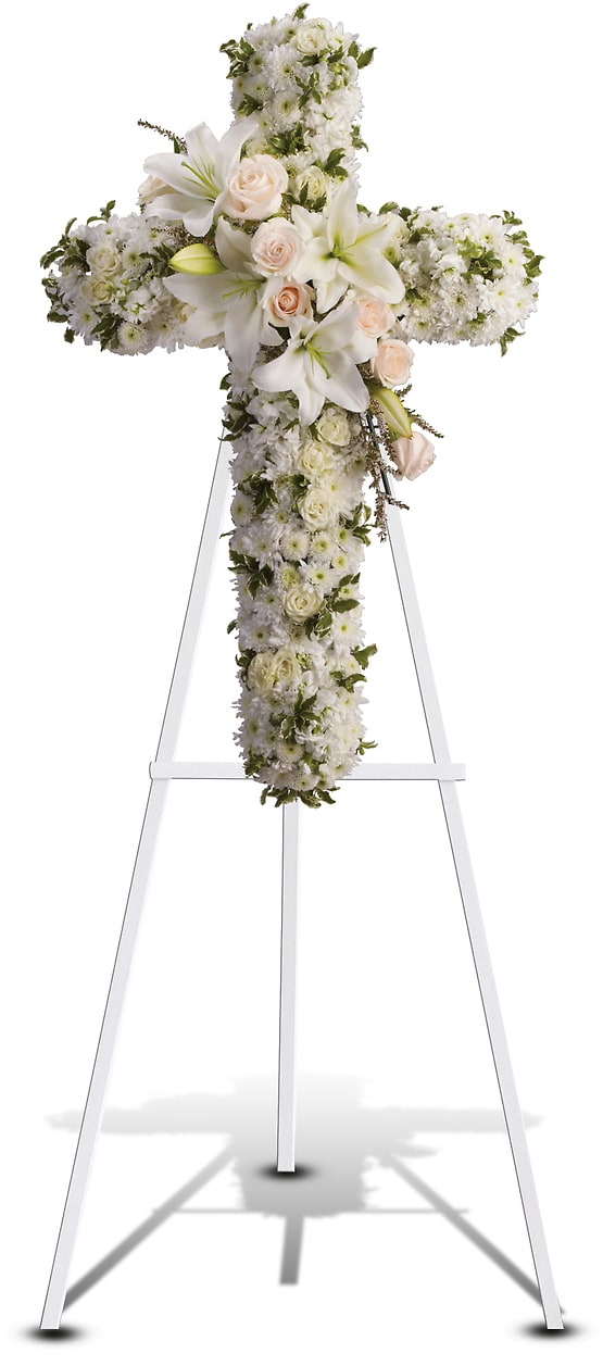 White floral cross on a stand with pale roses and lilies