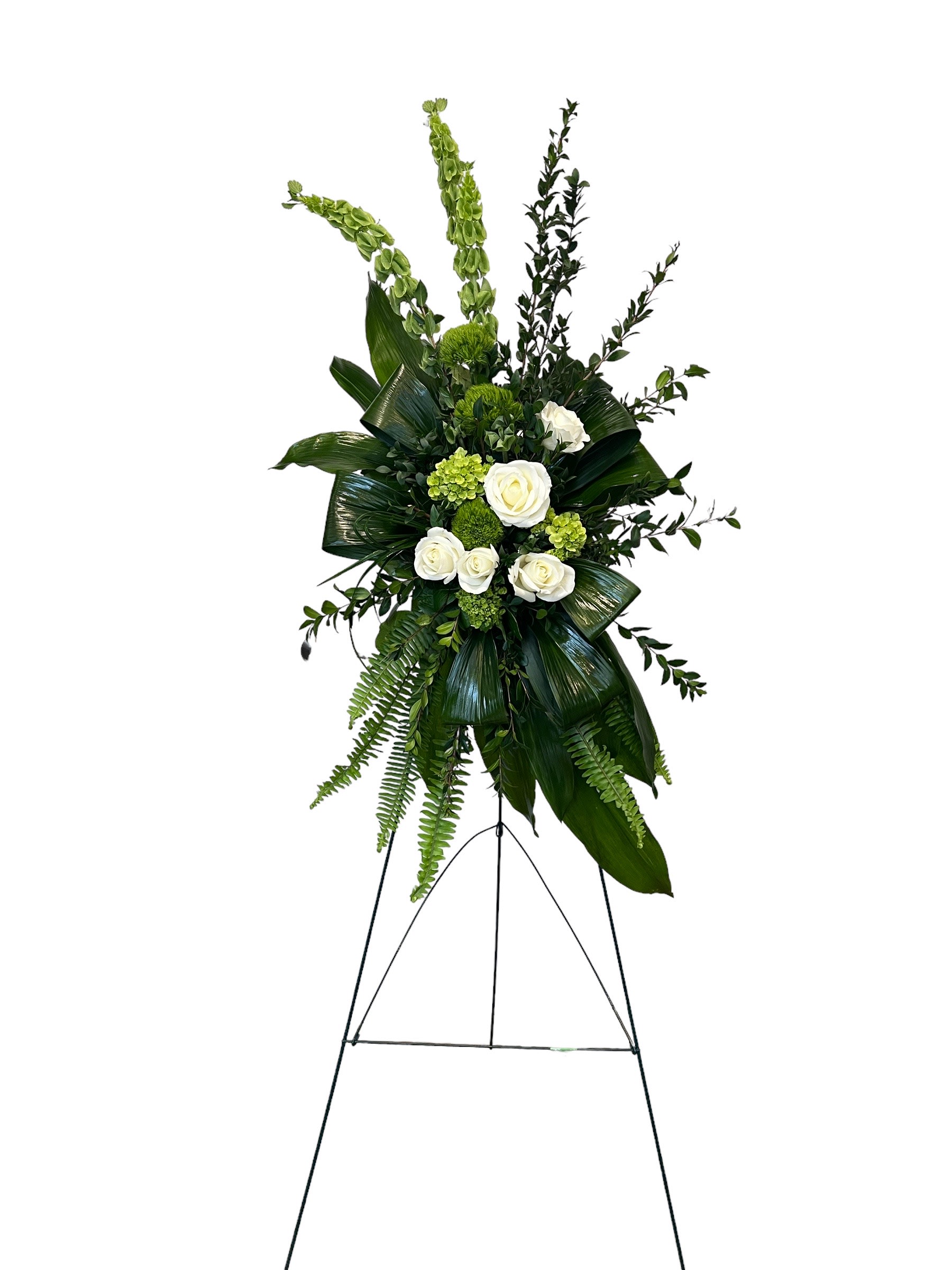 Tall standing floral spray with white roses and green foliage on an easel