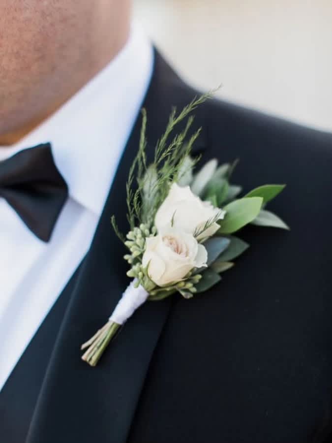 White rose boutonniere pinned to a black tuxedo lapel