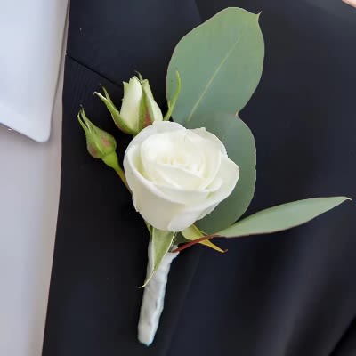 White rose boutonniere with green leaves on a dark suit