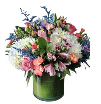Mixed bouquet of pink, white, and purple flowers in a green glass vase